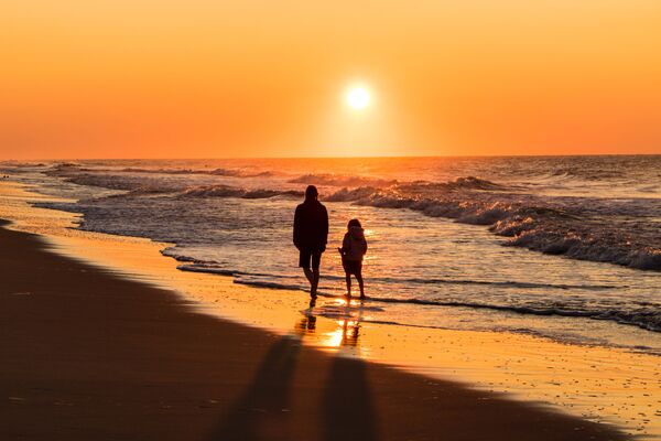 Paseo costero al atardecer con personas caminando de forma tranquila